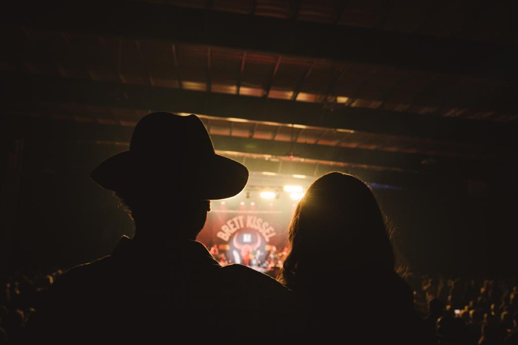 Silhouette of 2 people with concert stage in the background