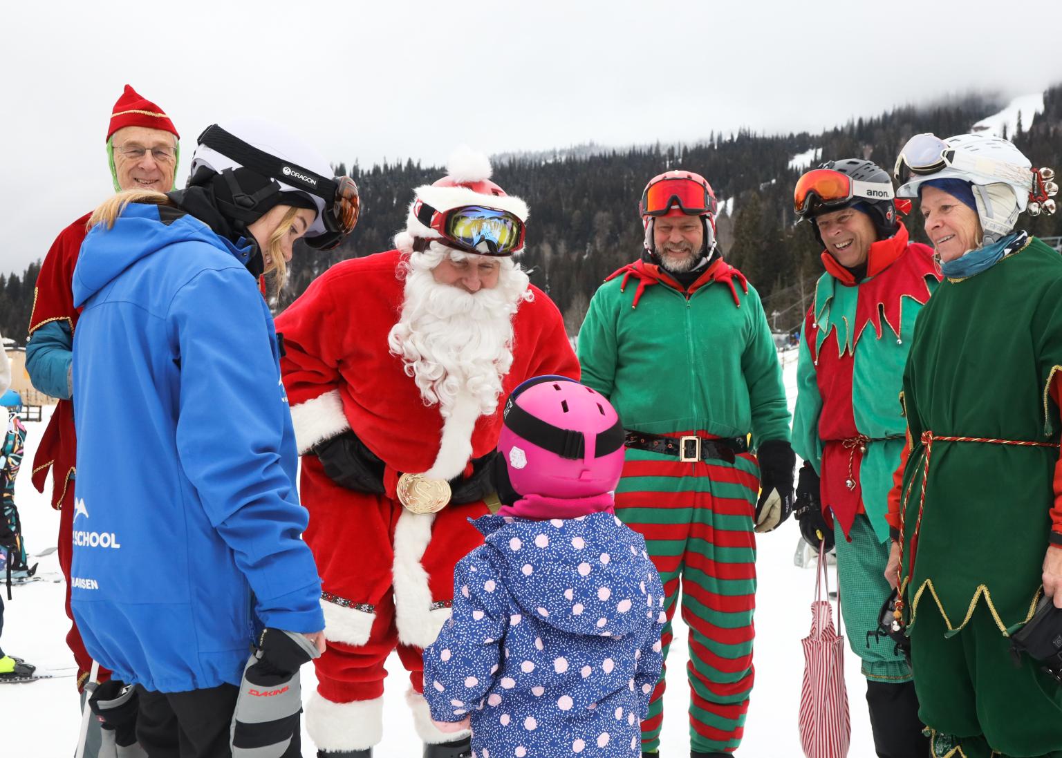 Santa and elves greeting a Sport's School employee and a child