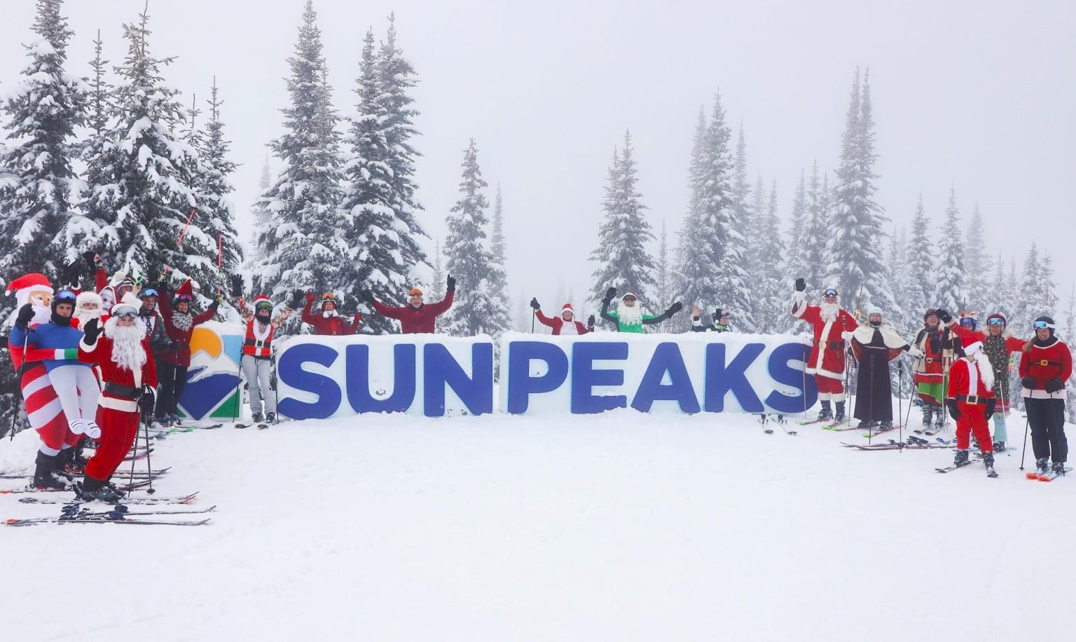 Santa Ski Day, many Santas having a group photo at the Sun Peaks sign