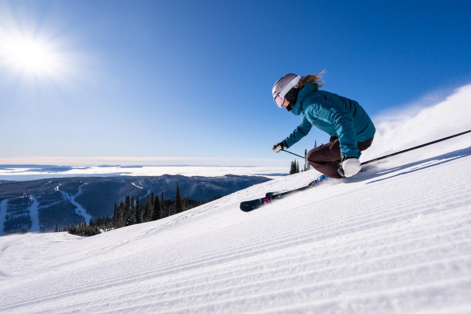 Skier riding down the mountain in powder with mountain views behind them