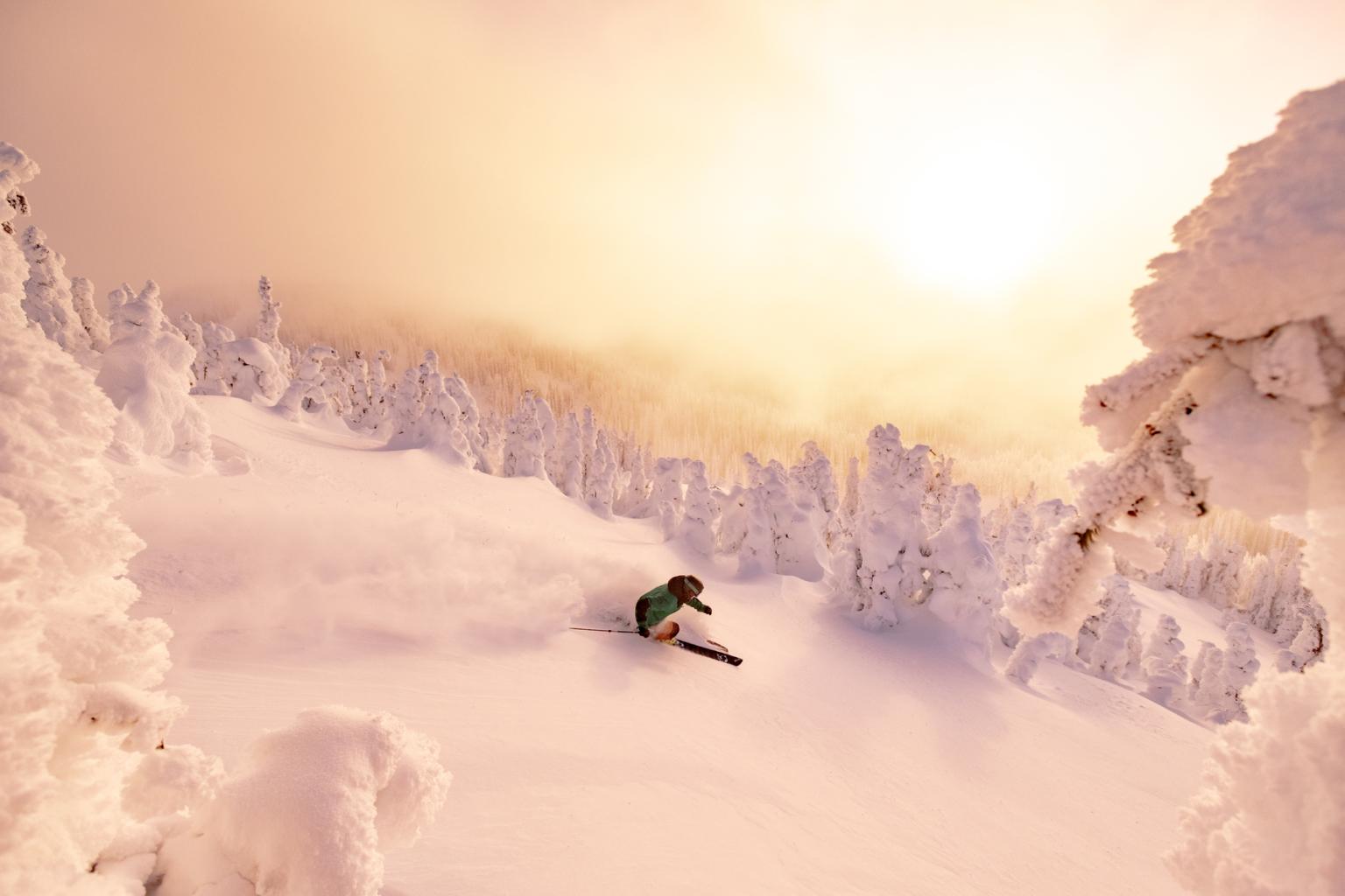 Skier descending the sunlit slopes of the West Bowl in Sun Peaks in the morning