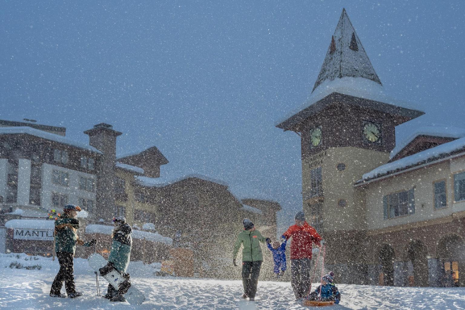 Family and skiers congregating in Sun Peaks village in the evening while snow falls