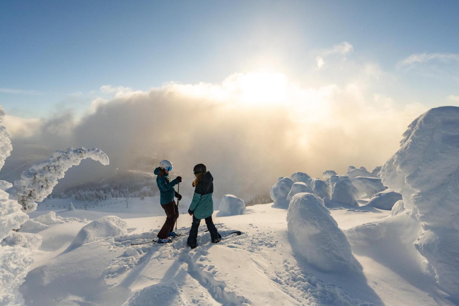 A skier and snowboarder talking at the Top of the World in Sun Peaks