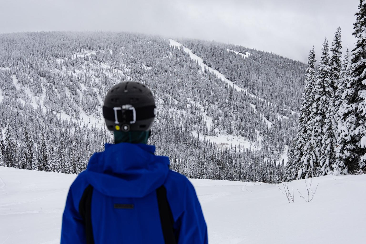 Person looking out to the mountain with snow and ski runs in the distance