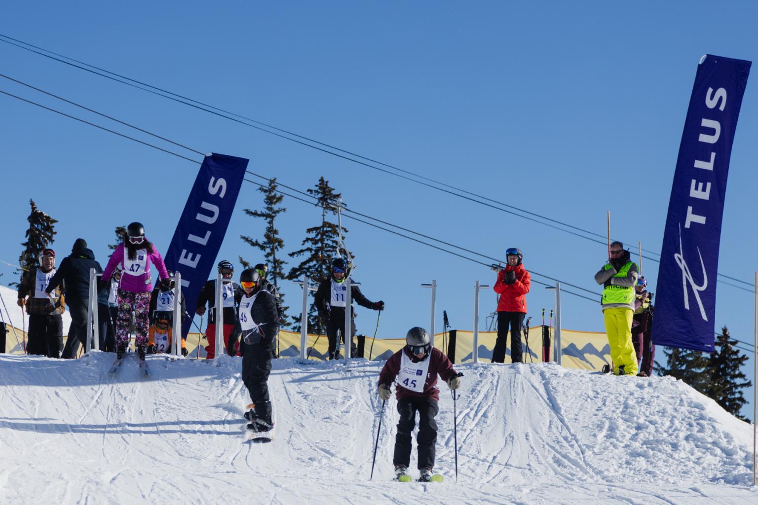 Skiers riding down a trail with TELUS flags around them