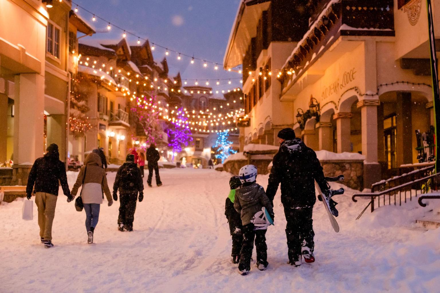 Family walking through a snowy sun peaks village at night