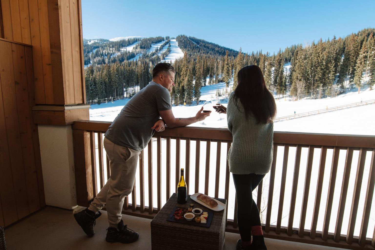 Couple enjoying wine and a cheese board on their lodging patio with mountain view
