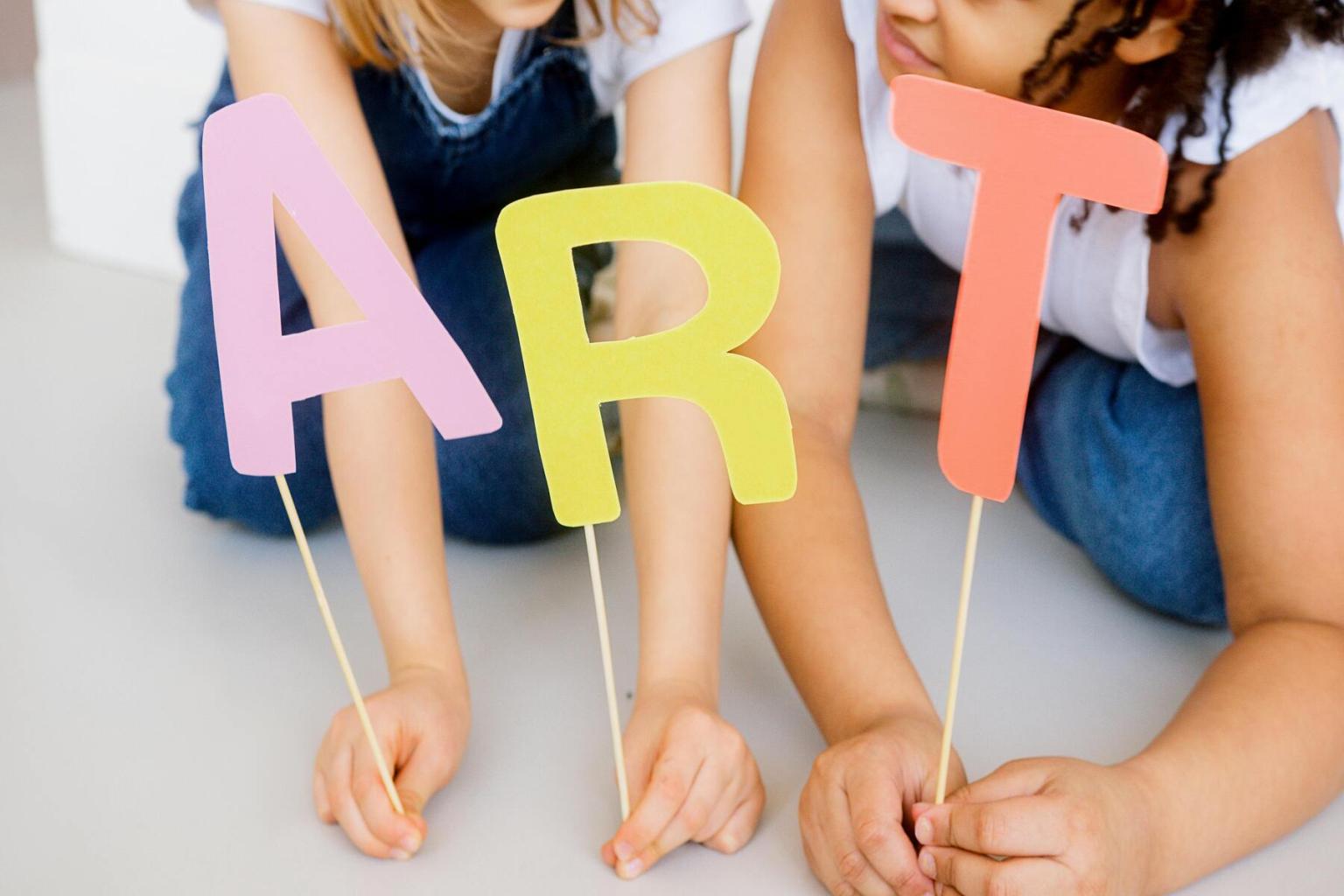 Children holding colorful letters spelling "ART"