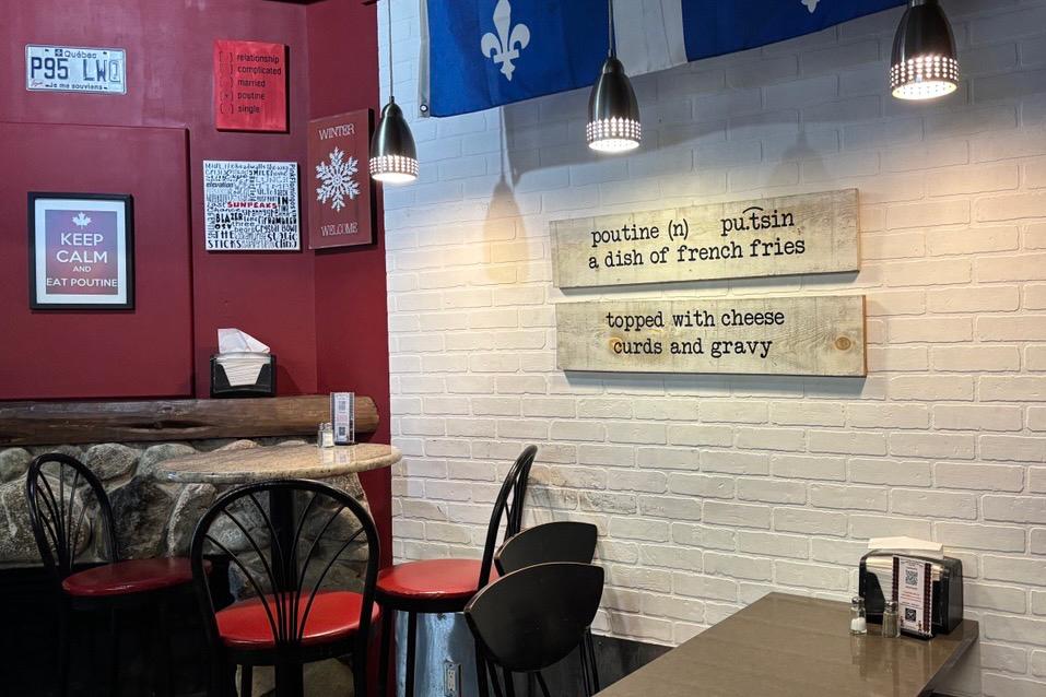 Chez Joe Poutine dining area with red and white walls, chairs, and Quebec flag decorations.