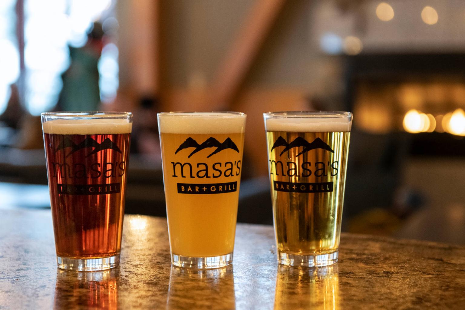 Three beers on a bar counter with a cozy, blurred background.