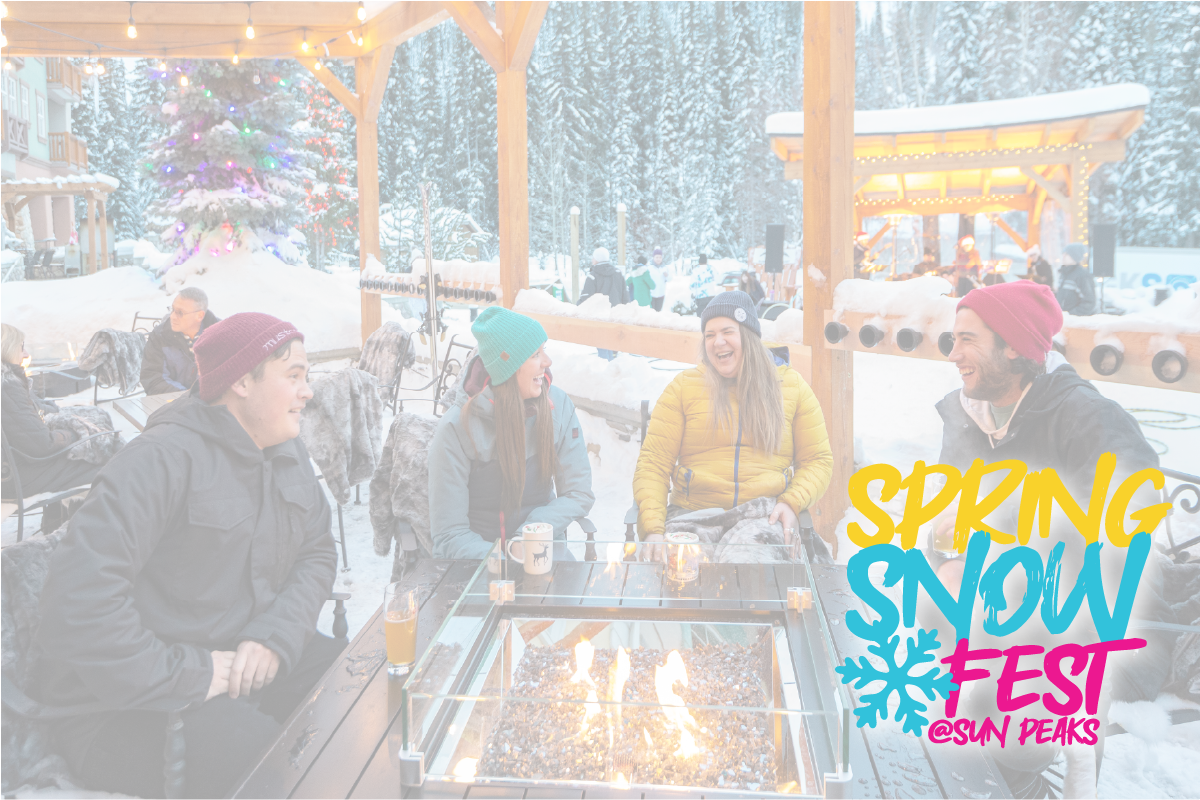 Group of friends laughing around an outdoor fire pit in snowy setting.