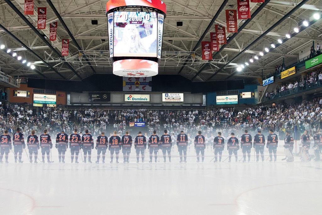 Hockey team lines up on the ice in a packed arena.