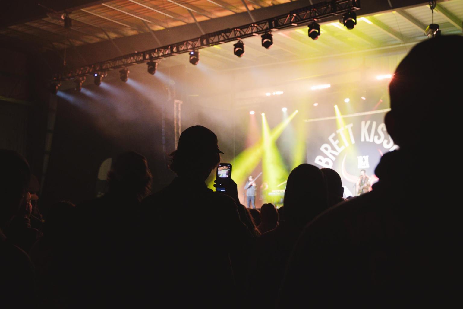 Concert crowd silhouetted against stage lights.