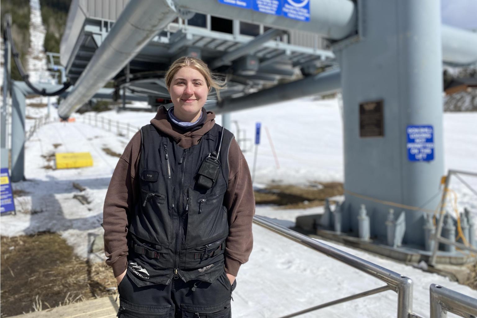 Person in a brown jacket stands at a snowy ski lift station.