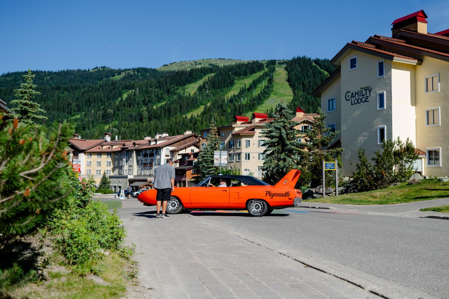 Orange classic car on a street in a mountain village.