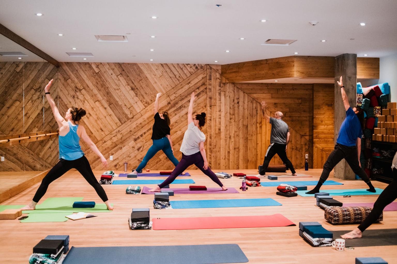 People practicing yoga in a studio with wooden walls.