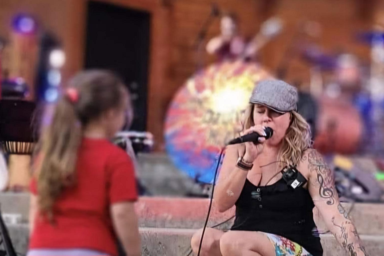 Singer performing on stage with a girl watching, colorful background.