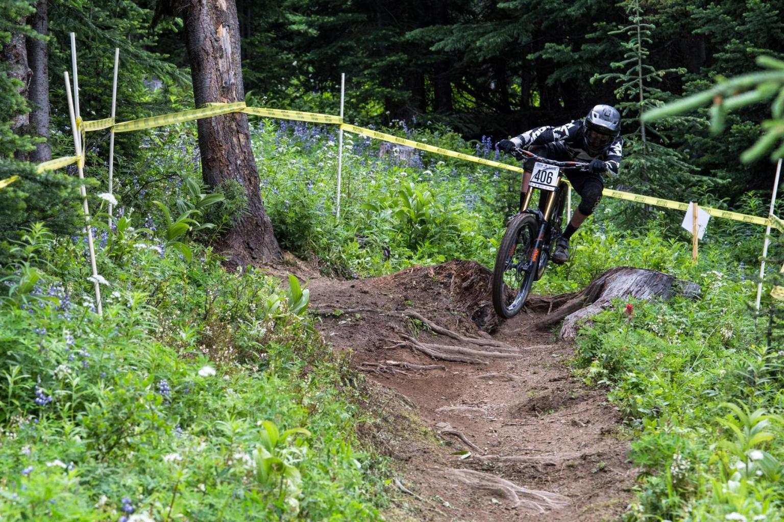 Mountain biker racing downhill on a forest trail.