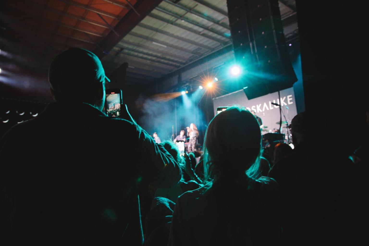 Concert audience watching performers on stage with bright lights.