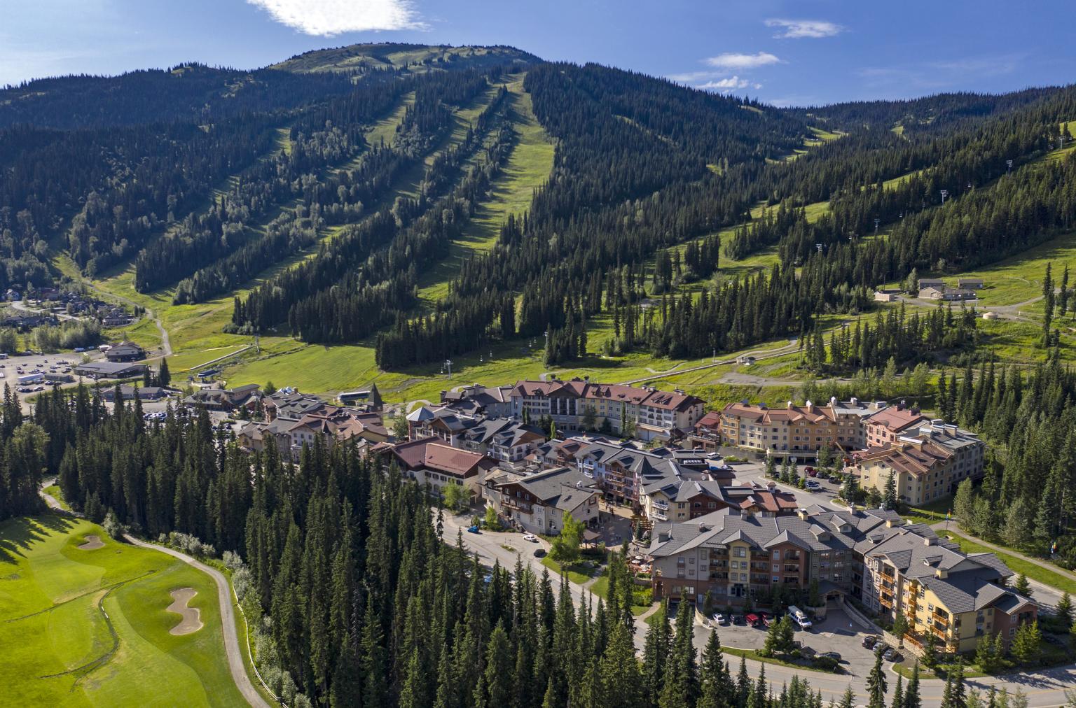 Village nestled in a green mountainous landscape on a sunny day.