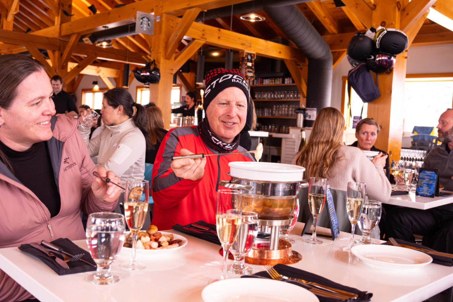People enjoying fondue at a cozy, wooden restaurant.