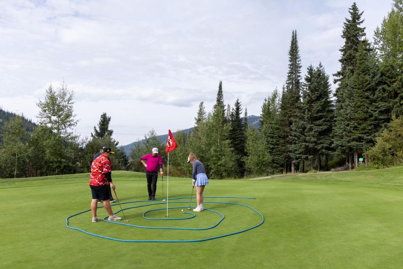 Three people on a golf course, surrounded by a looped garden hose obstacle.