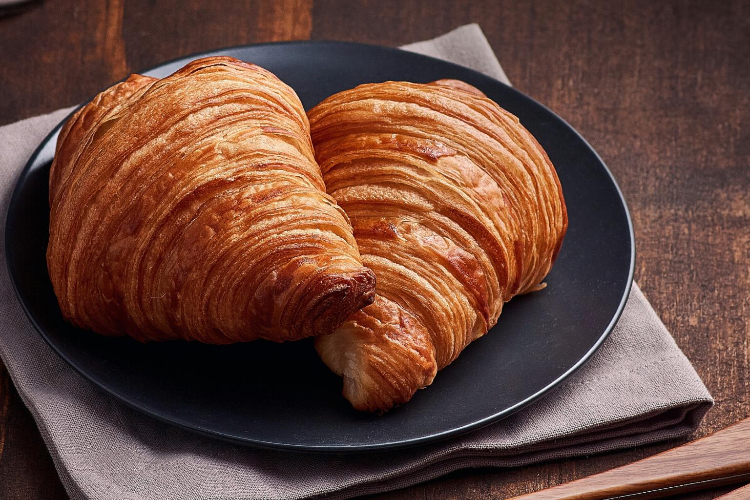 Two croissants on a black plate with a napkin.