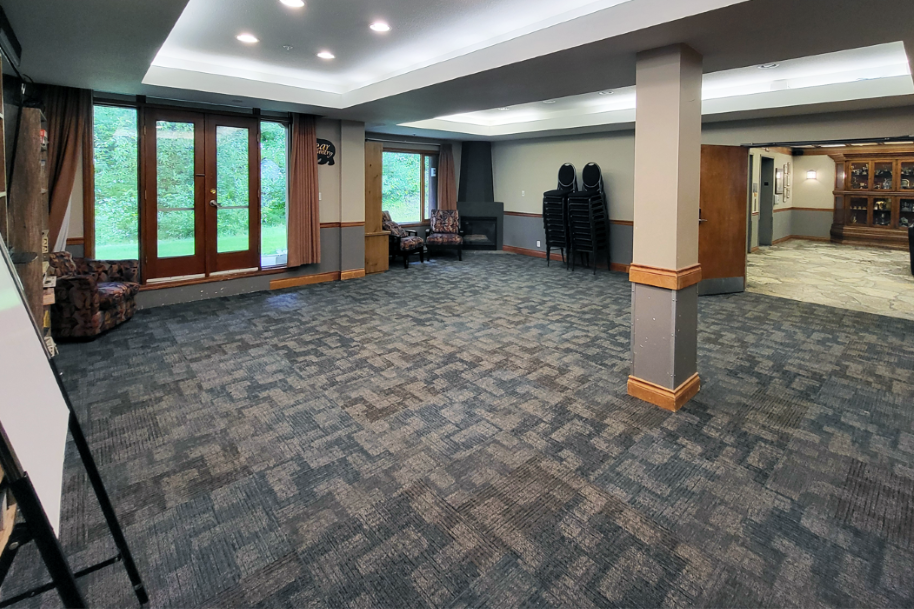 Spacious meeting room with carpet, large windows, and wooden accents.