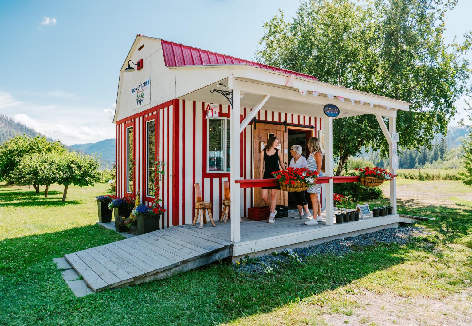 Red and white striped farm market stand with two smiling people outside.