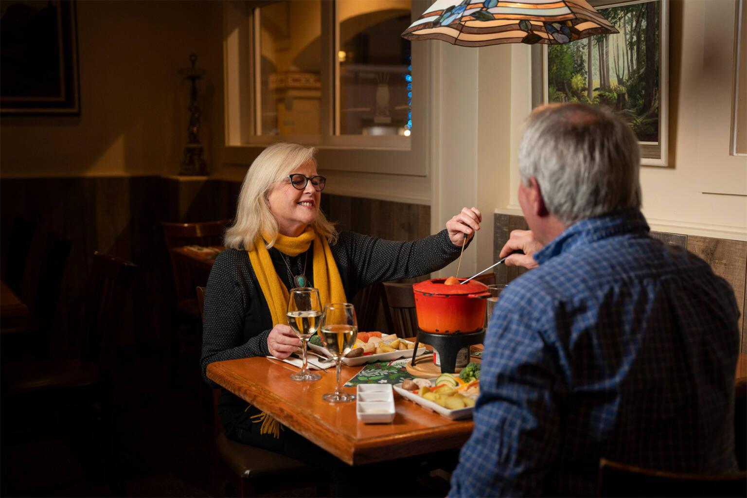 Couple enjoying fondue at a cozy restaurant table.