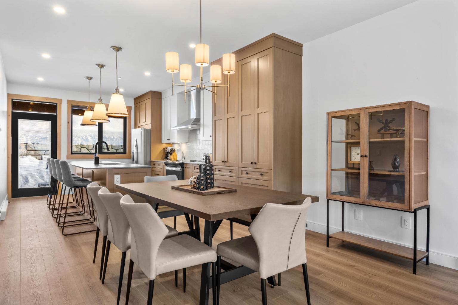Modern dining room with wooden table, beige chairs, and pendant lights.