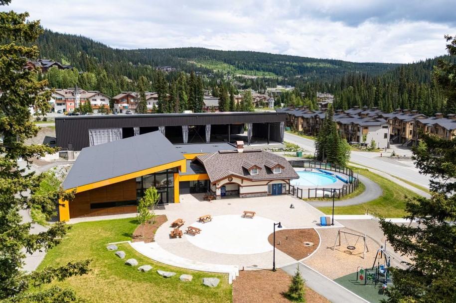 Conference Centre with modern buildings, playground, pool, and trees in a mountainous area.