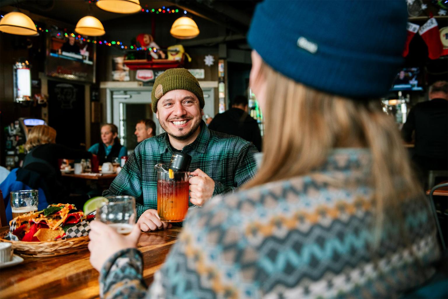 Two people in a cozy bar, smiling and enjoying drinks.