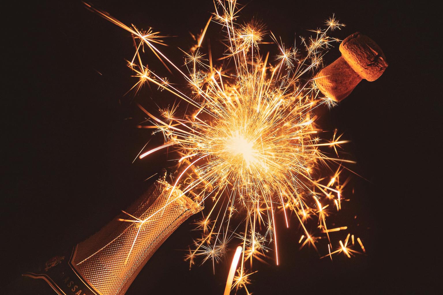 Champagne bottle with sparkling fireworks exploding from the top.