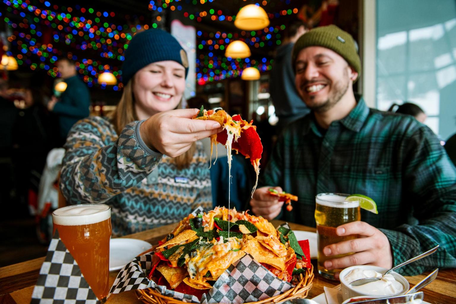 Couple enjoying nachos and drinks in a festive restaurant setting.