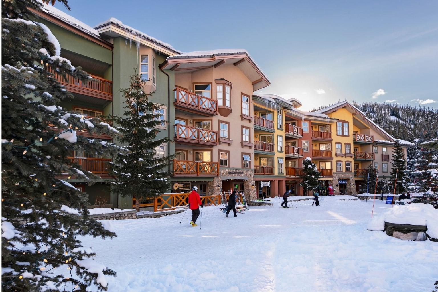 Snowy village street, people walking, colorful buildings in background.