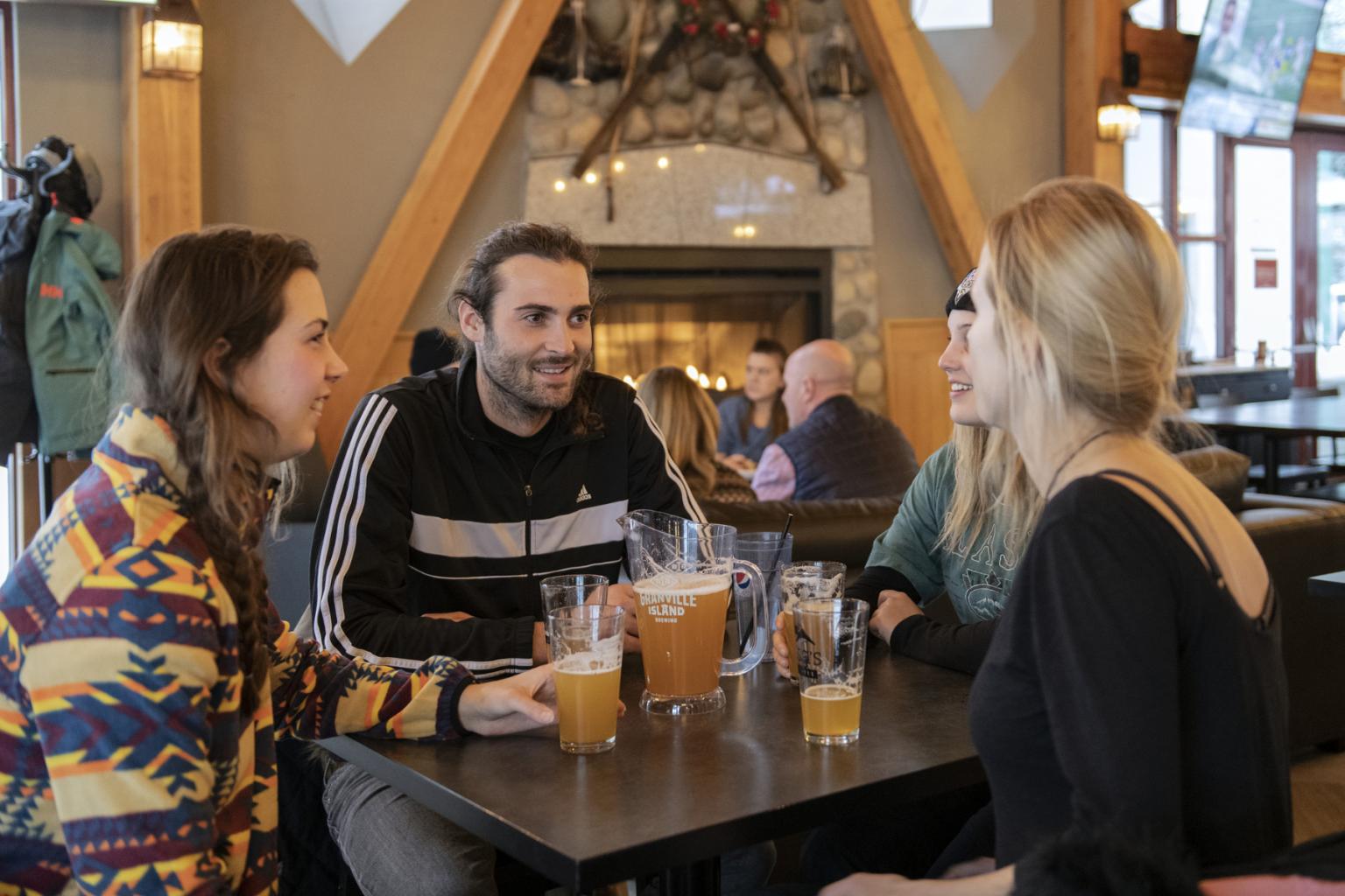 Cozy pub setting with four people chatting and enjoying drinks.