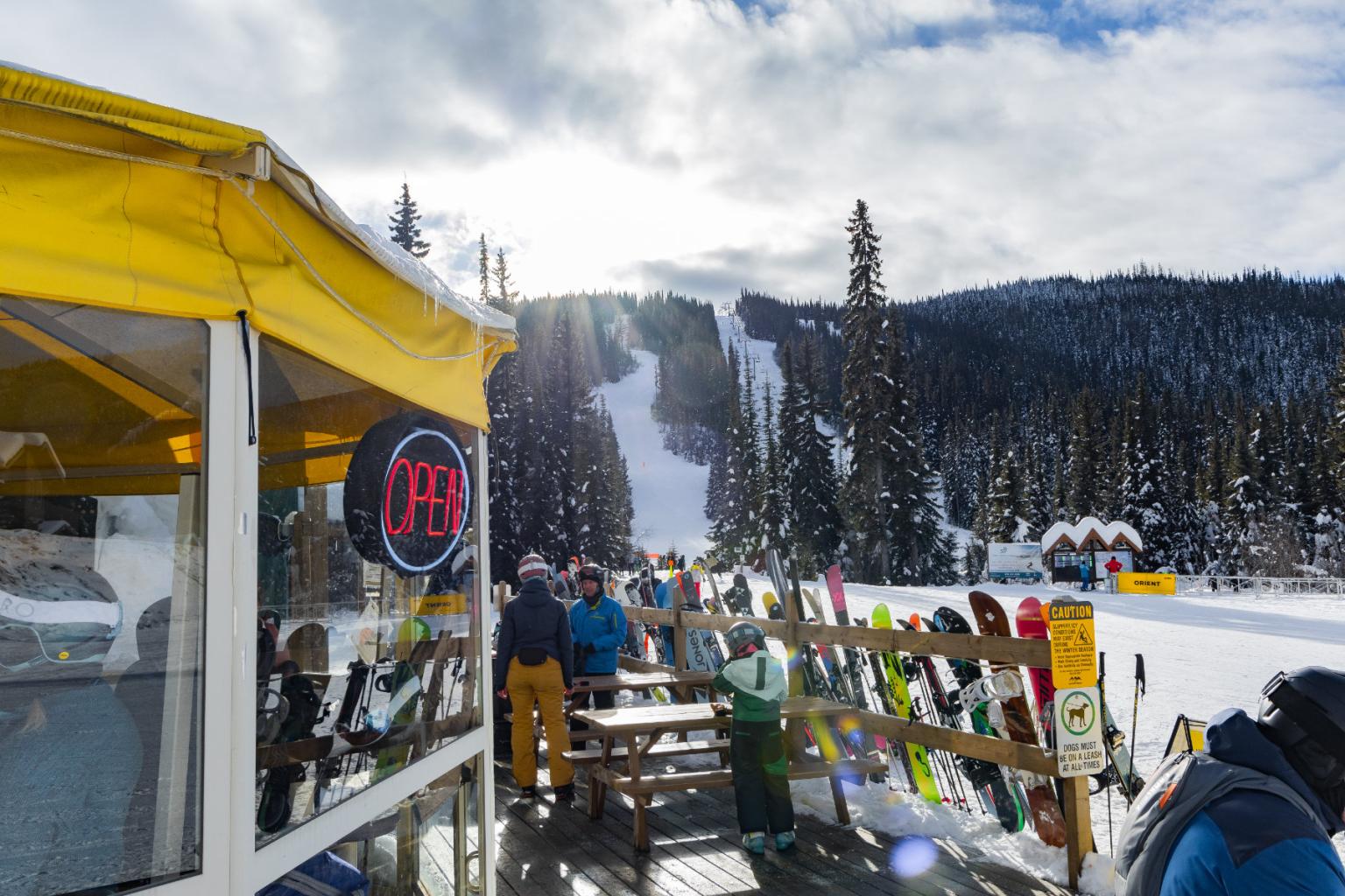 Ski resort with snowy slopes, skiers, and a bright yellow cafe.