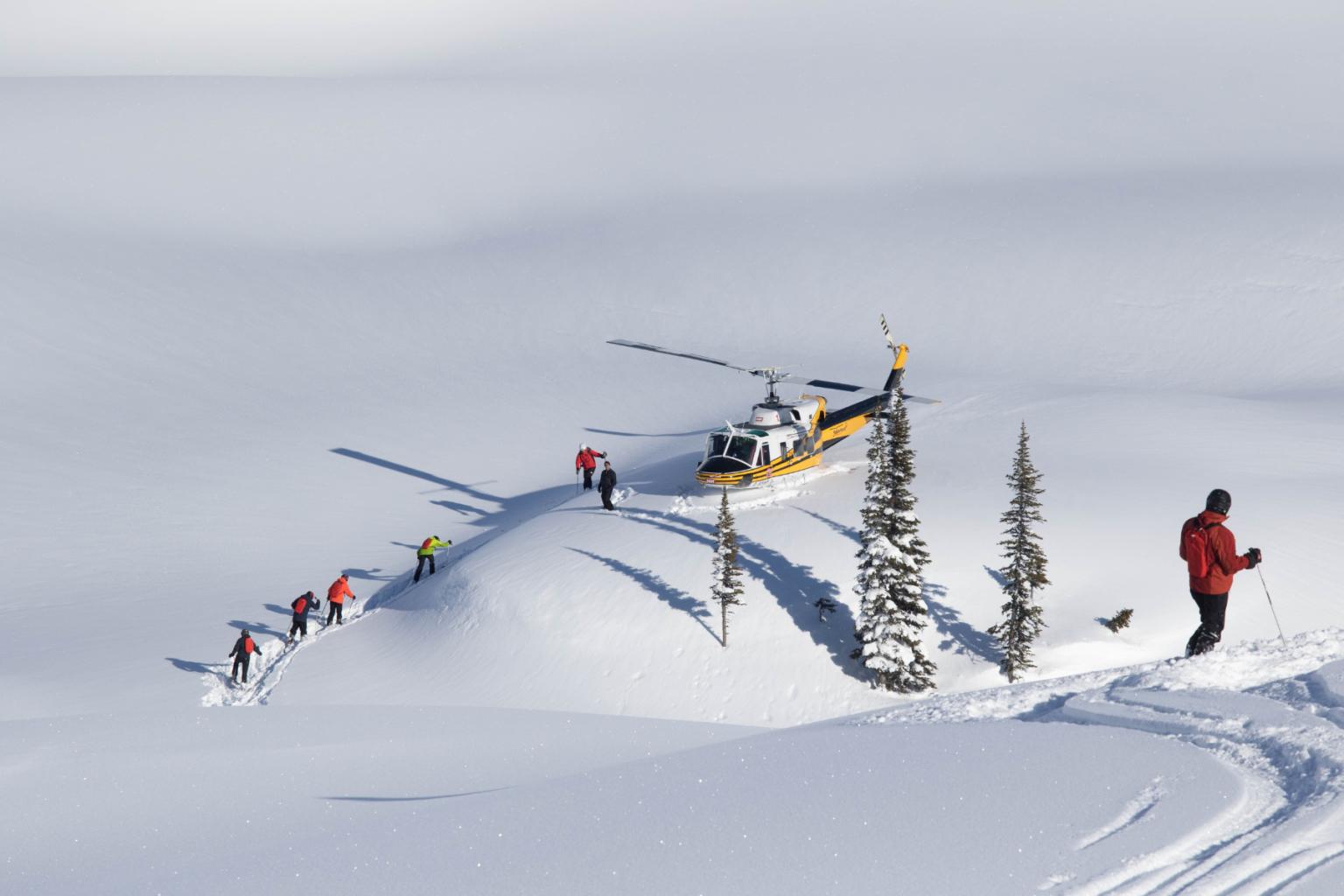Skiers and a helicopter on snowy mountain landscape.
