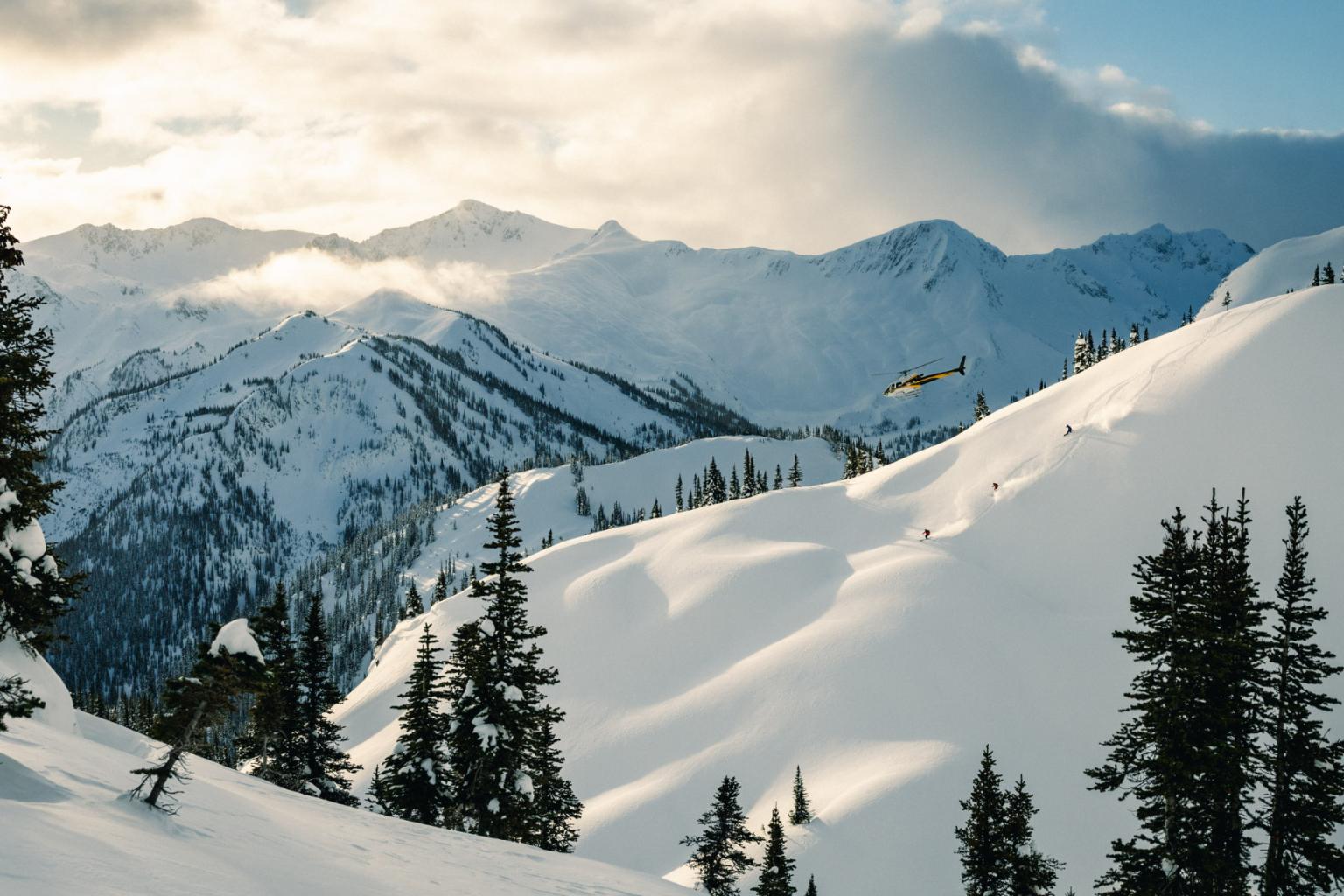 Snowy mountain landscape with pine trees and helicopter.