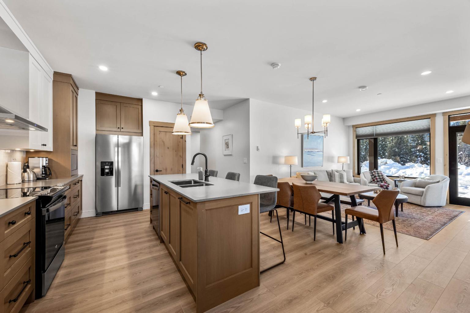 Modern open-plan kitchen and living room with wooden accents, dining area, and large windows.