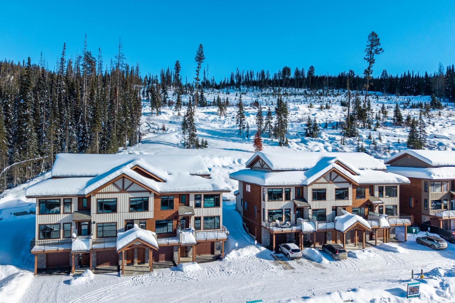 Snow-covered Switchback Creek townhouses with a forest backdrop under a clear blue sky.
