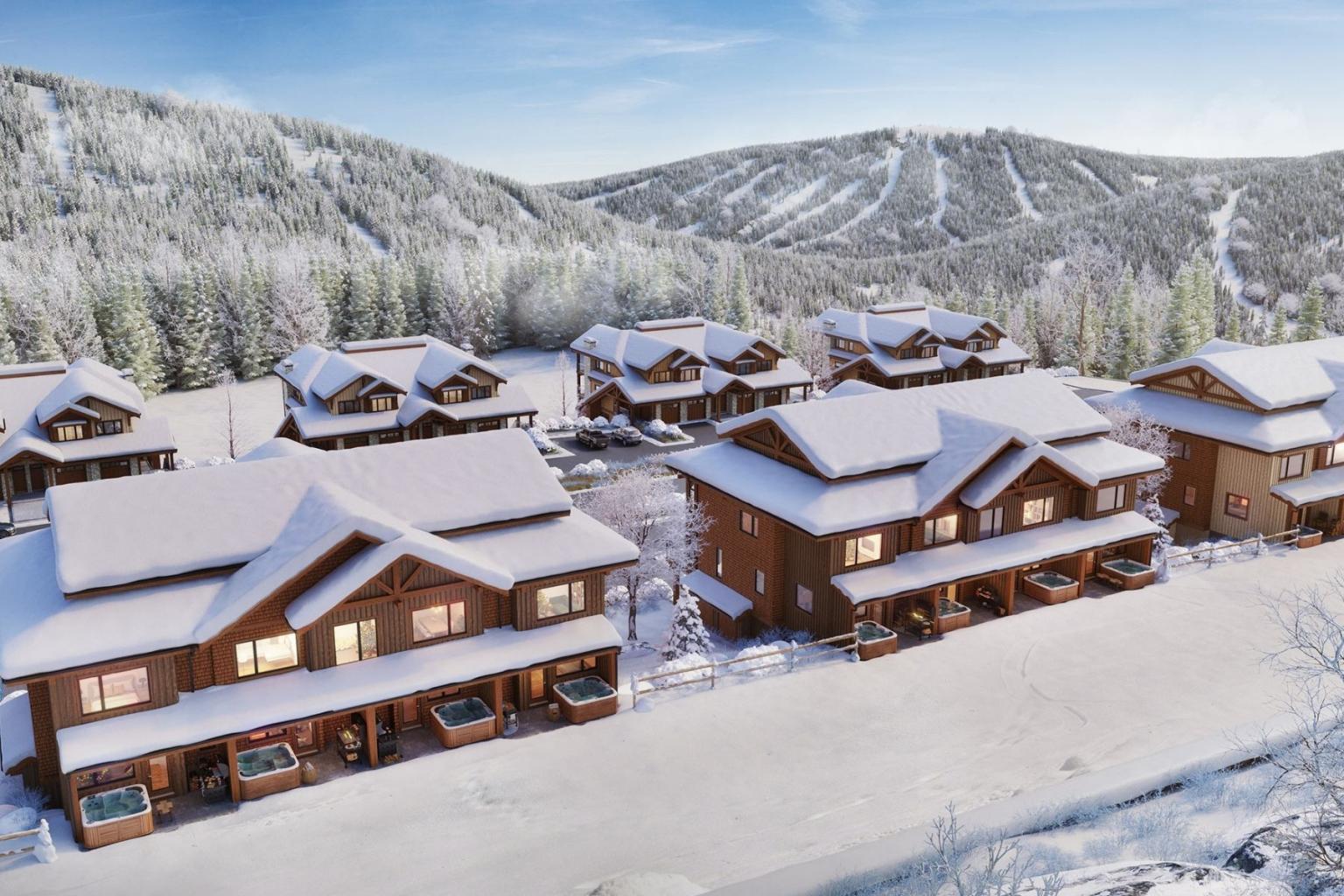 Snow-covered homes at Switchback Creek with snowy mountains in the background.
