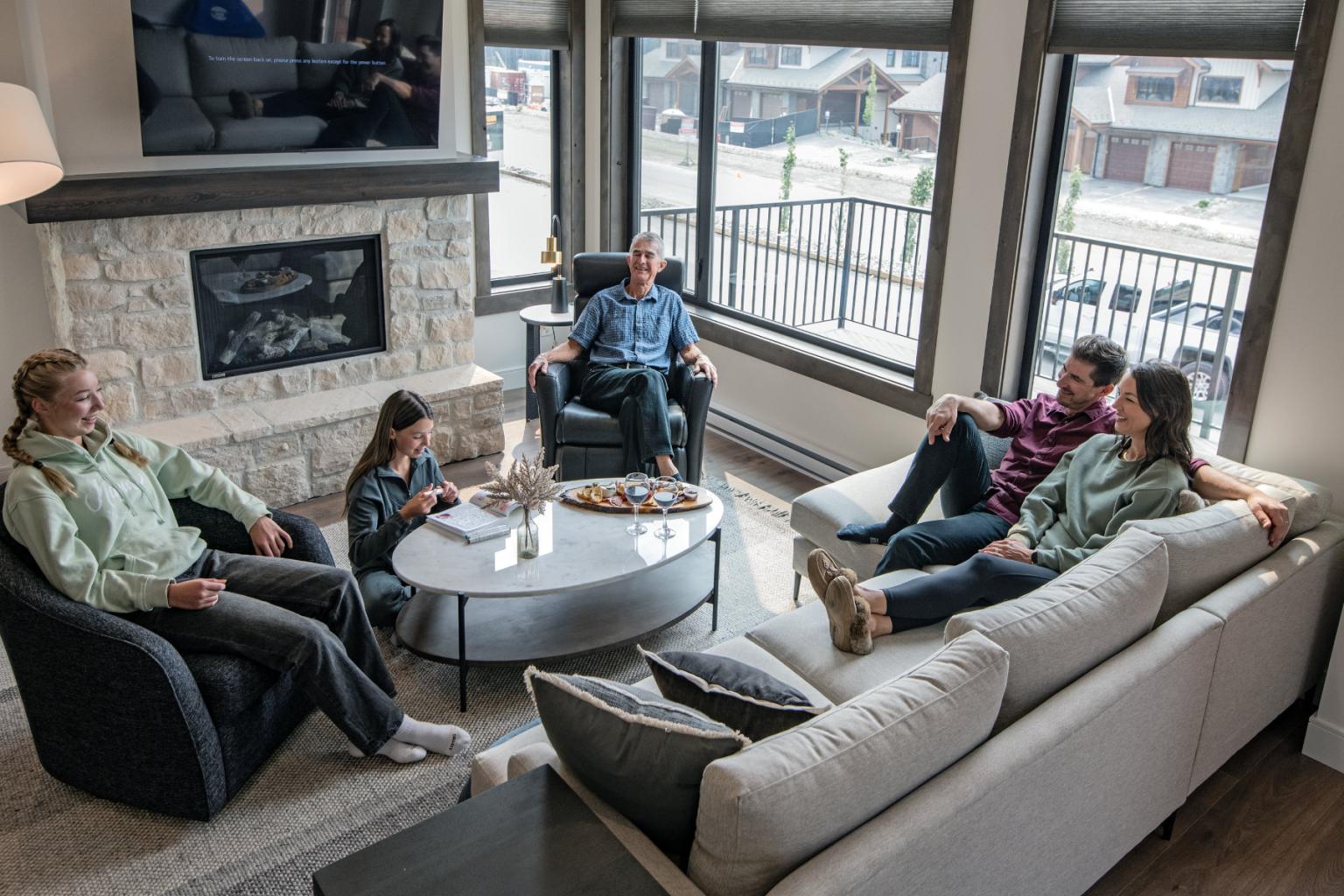 Family sitting in a cozy living room with large windows and a fireplace.