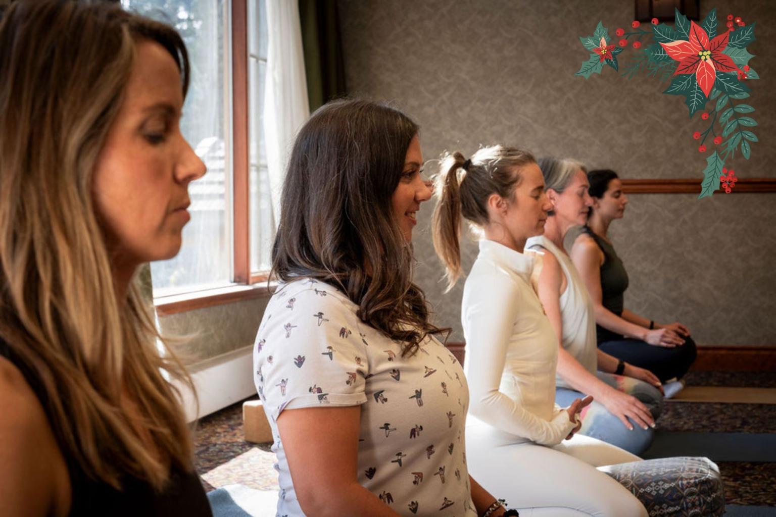 Women meditating in a room with holiday decor accents.