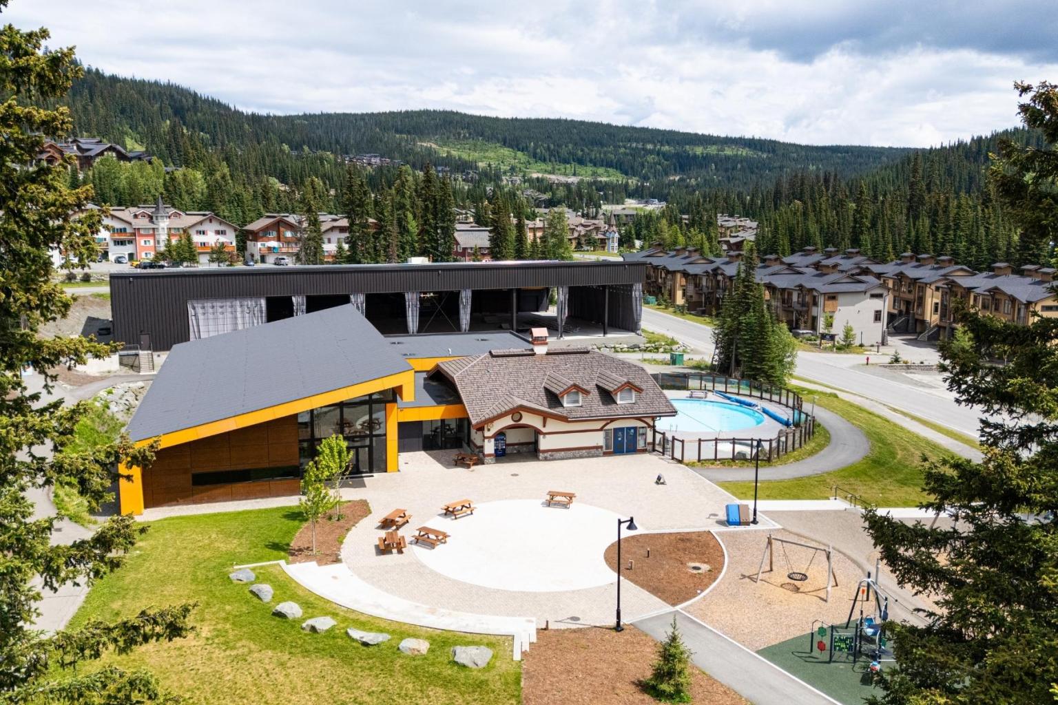 Sun Peaks Centre surrounded by trees and houses, with pool and playground.