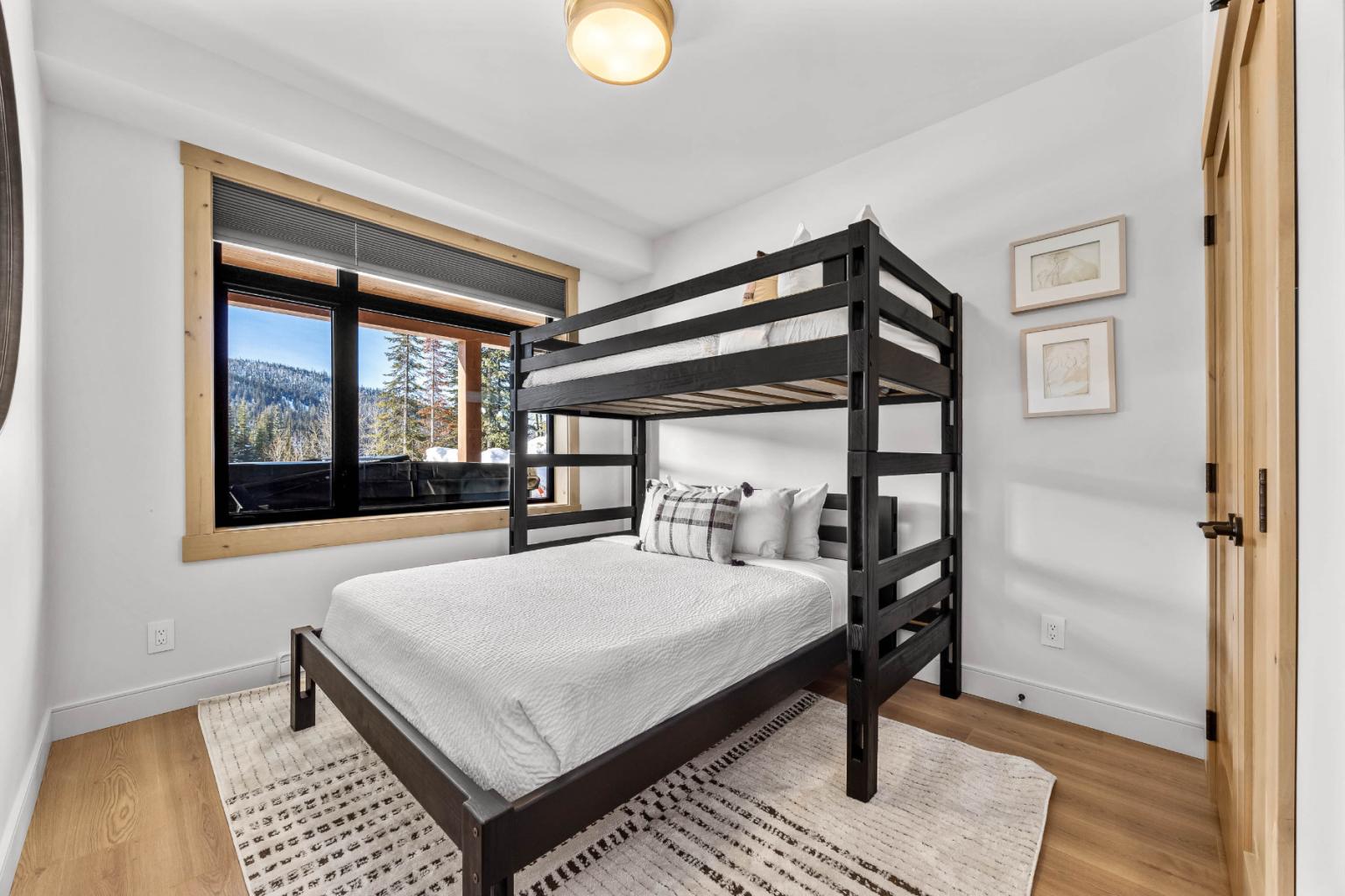 A bright room in the Switchback Creek condo features a bunk bed, minimalist décor, and a window with mountain views.