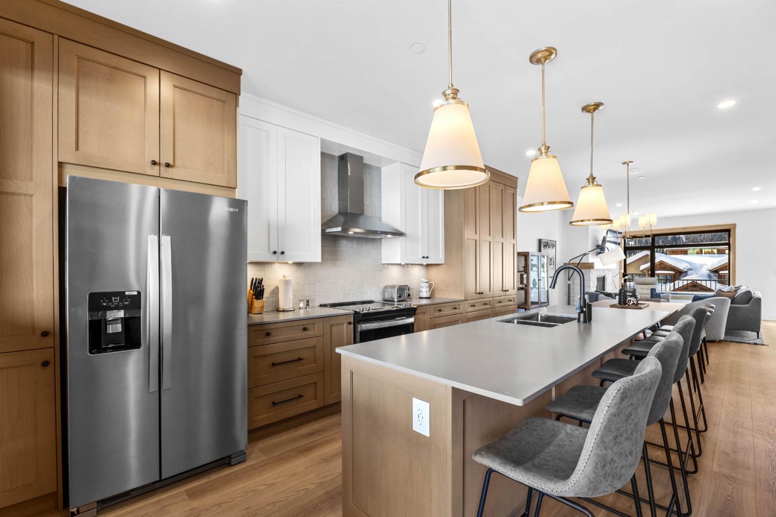 A modern kitchen in the Switchback Creek townhome features stainless steel appliances, wooden cabinets, and pendant lighting.