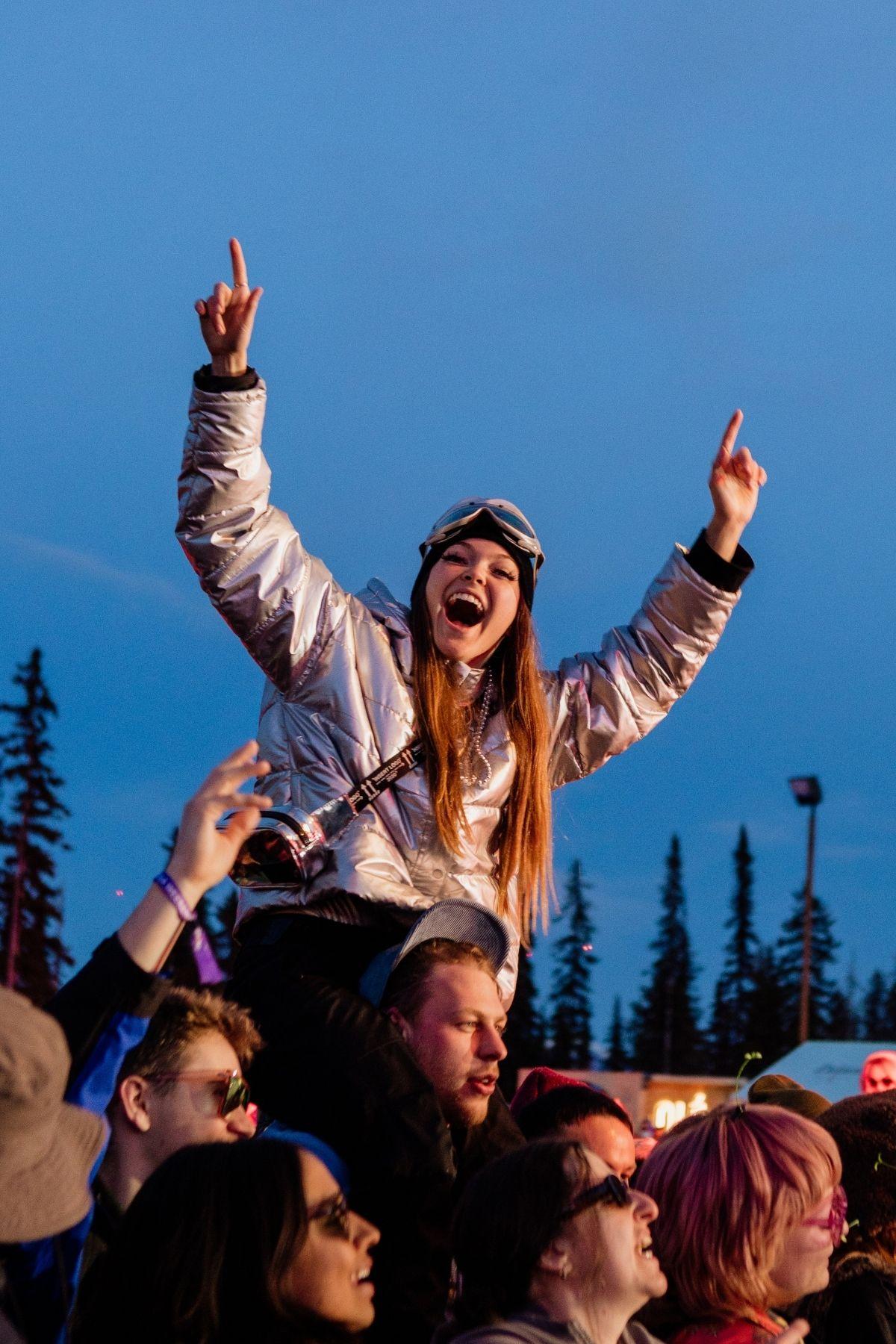 Cheering crowd at an outdoor concert during dusk.