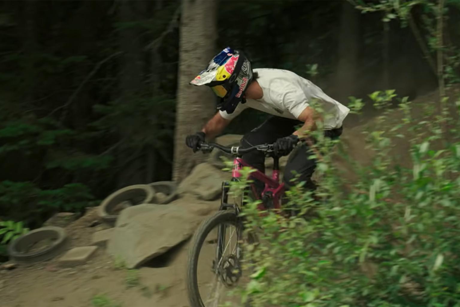 Mountain biker racing downhill in a forest trail.